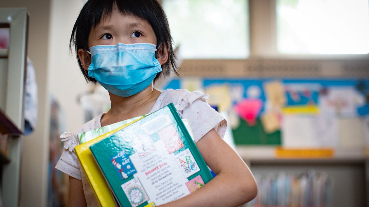 young girl wearing face mask in library