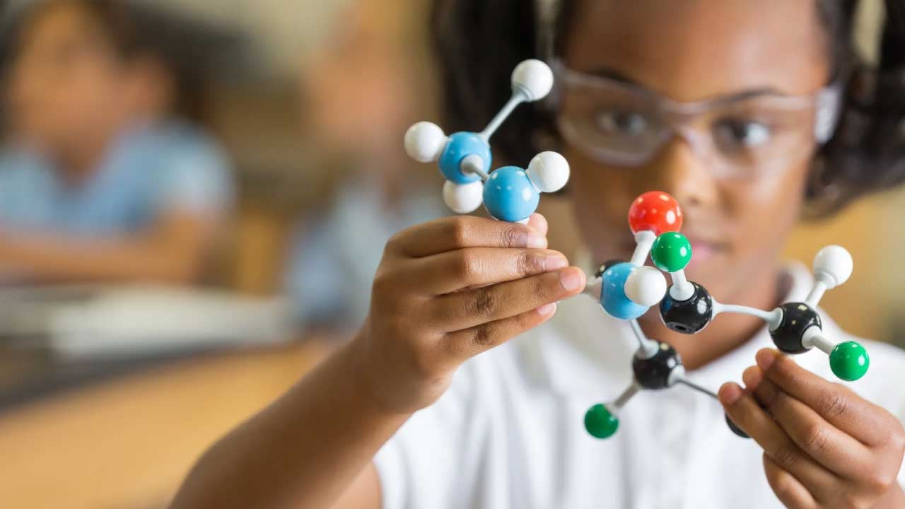 Young female student looking at chemistry molecules