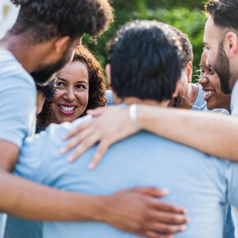 The diverse group of friends hug each other as they finish up their volunteer event.